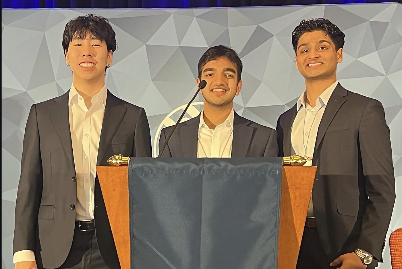 Three brothers at the podium at an Alpha Kappa Psi conference
